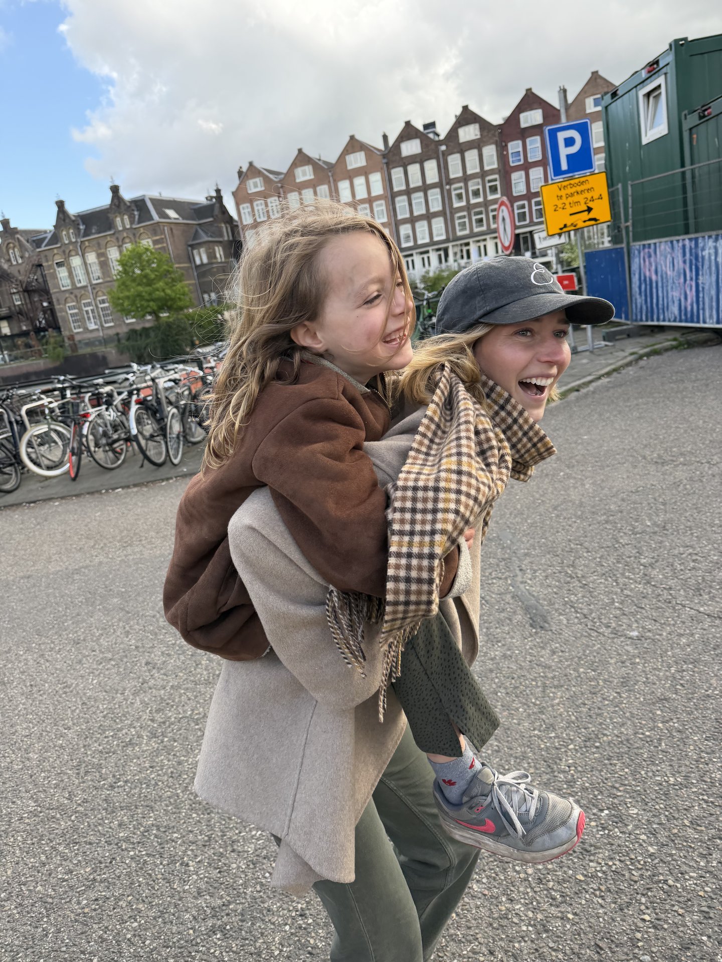 A joyful moment unfolds on Zeeburgerpad, Centrum, Amsterdam, as an adult gives a child a piggyback ride, both laughing heartily